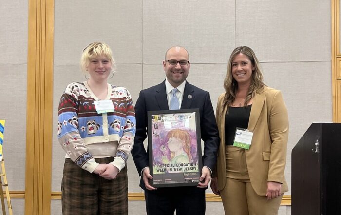 Special Education Week Grand Prize Winner Catherine M. of Holmstead School in Ridgewood poses alongside her award-winning artwork, held by New Jersey Department of Education Commissioner Kevin Dehmer joined with ASAH External Affairs Director Stephanie Summers.